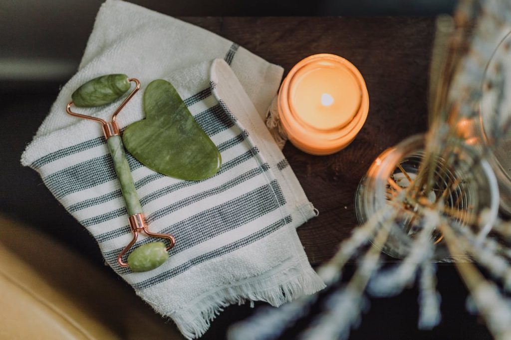 瑞容坊美容養生 A serene spa setup featuring a jade roller, gua sha, towel, and candle for ultimate relaxation.